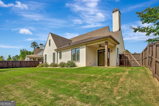 rear view of house featuring a lawn and ceiling fan