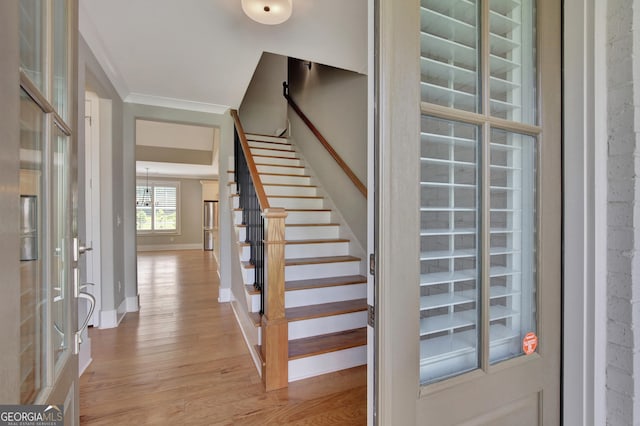 staircase with wood-type flooring and ornamental molding