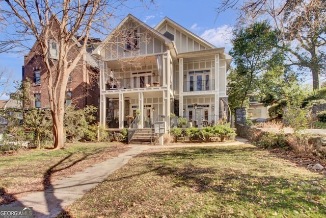 view of front facade with a balcony, french doors, and a front yard