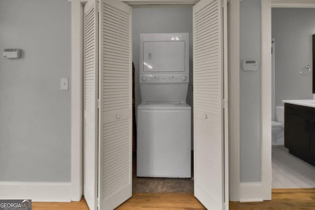 laundry room featuring stacked washer / dryer and light hardwood / wood-style flooring