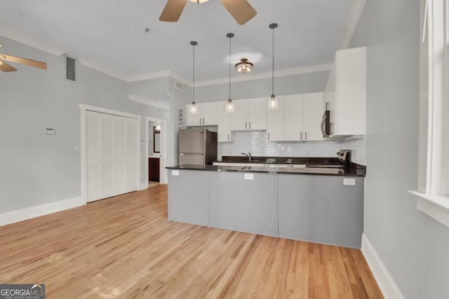 kitchen with pendant lighting, stainless steel appliances, decorative backsplash, white cabinetry, and ceiling fan