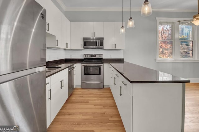 kitchen with stainless steel appliances, decorative light fixtures, white cabinetry, ceiling fan, and ornamental molding