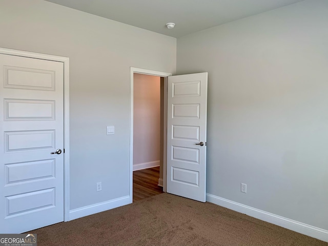 unfurnished bedroom featuring dark carpet and a closet