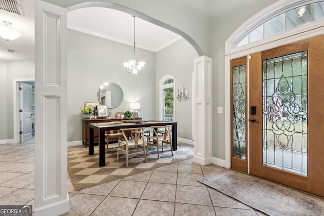 foyer entrance featuring ornamental molding, a notable chandelier, and light tile patterned floors