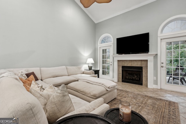 living room with high vaulted ceiling, light tile patterned flooring, ceiling fan, and a tile fireplace