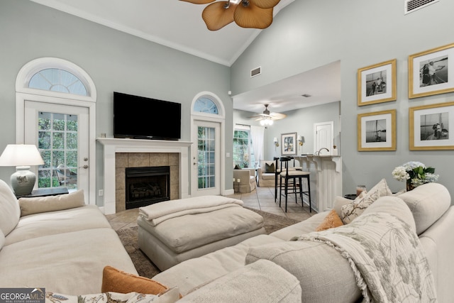 tiled living room featuring high vaulted ceiling, a fireplace, and ceiling fan