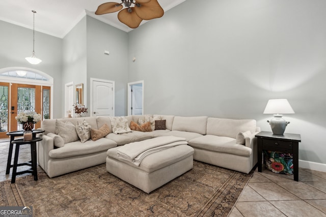 tiled living room featuring a high ceiling, ceiling fan, and ornamental molding