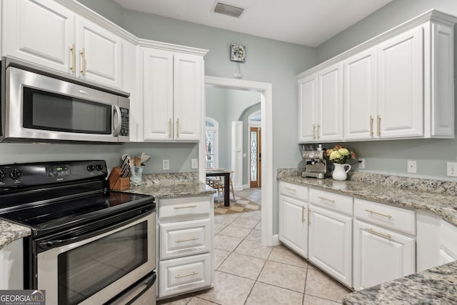 kitchen featuring appliances with stainless steel finishes, white cabinets, light stone counters, and light tile patterned floors