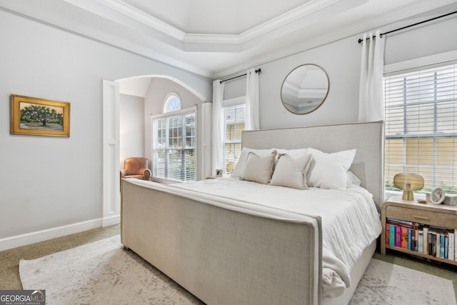 bedroom with ornamental molding, a tray ceiling, and light carpet