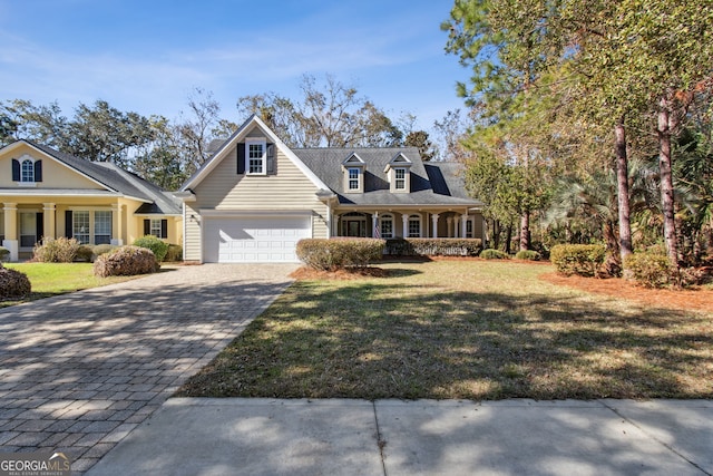 cape cod-style house featuring covered porch, a front lawn, and a garage