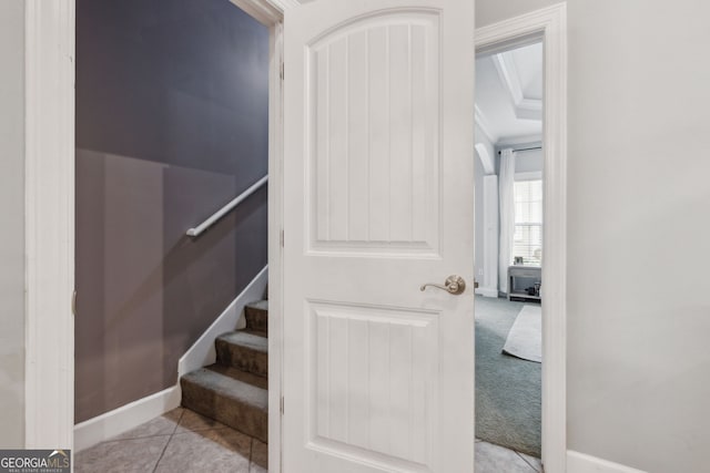 stairway featuring crown molding and tile patterned floors