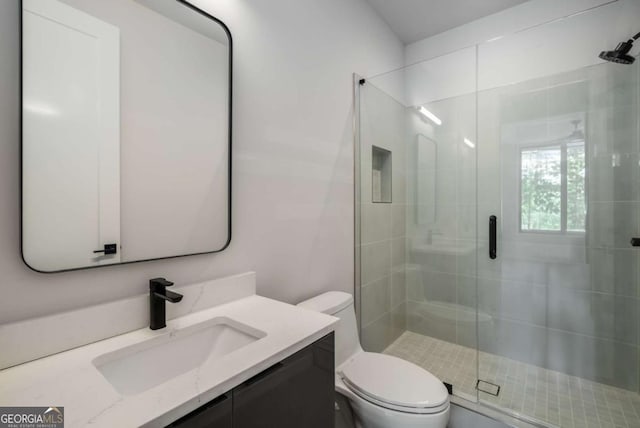 bathroom featuring toilet, a shower with door, and vanity