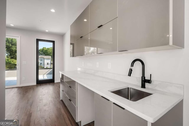 kitchen featuring sink, dark hardwood / wood-style flooring, and light stone countertops