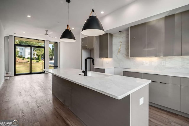 kitchen featuring hanging light fixtures, backsplash, gray cabinetry, ceiling fan, and sink