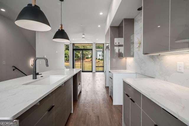 kitchen with sink, light stone counters, tasteful backsplash, expansive windows, and hanging light fixtures