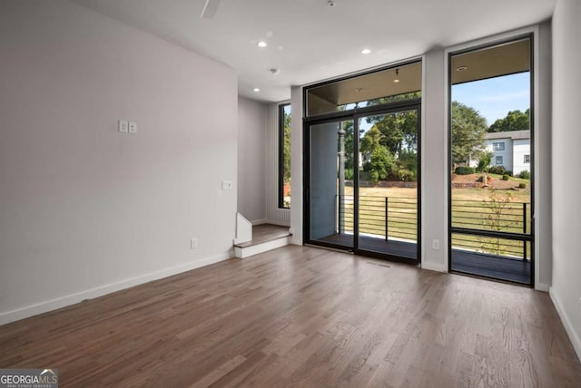 unfurnished room featuring floor to ceiling windows and hardwood / wood-style floors