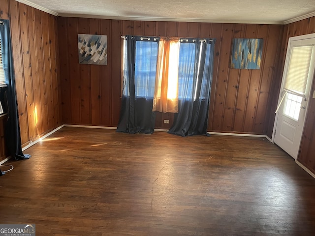 interior space featuring a textured ceiling, dark hardwood / wood-style flooring, and wood walls