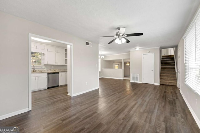 unfurnished living room with ceiling fan with notable chandelier, dark hardwood / wood-style flooring, and a textured ceiling