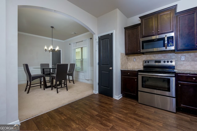 kitchen with a chandelier, appliances with stainless steel finishes, dark wood-type flooring, decorative light fixtures, and backsplash