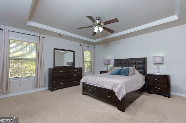 bedroom with ornamental molding, ceiling fan, a tray ceiling, and light carpet