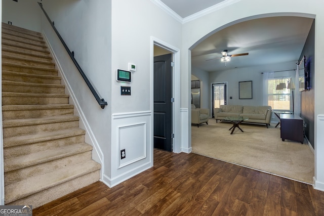 stairway with ornamental molding, ceiling fan, and wood-type flooring