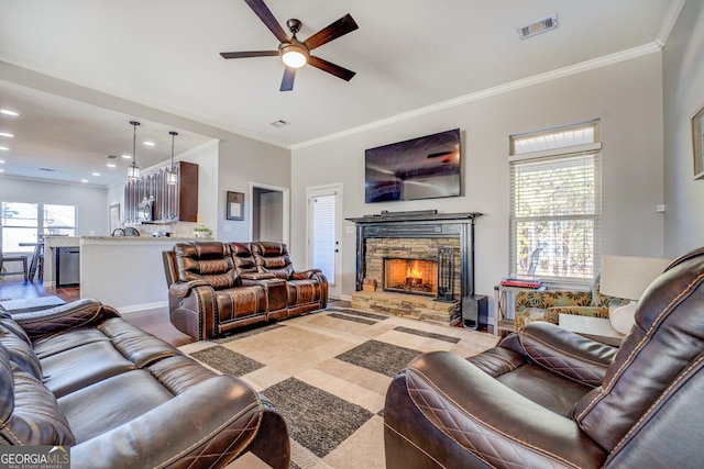 living room featuring ceiling fan, a healthy amount of sunlight, a stone fireplace, and ornamental molding