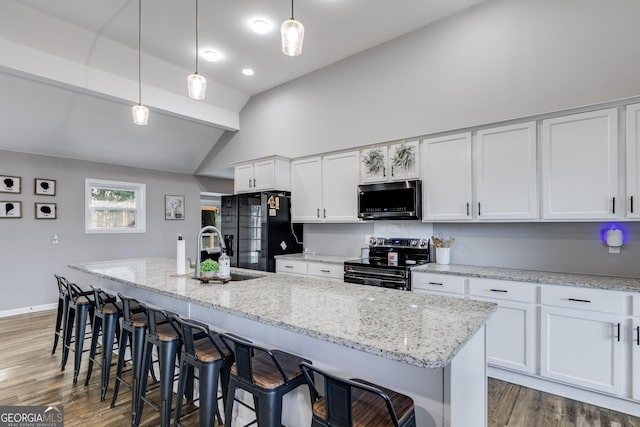 kitchen with a center island with sink, range with electric cooktop, black fridge, sink, and white cabinetry