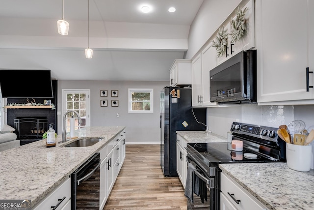 kitchen with light stone counters, pendant lighting, black appliances, white cabinetry, and sink