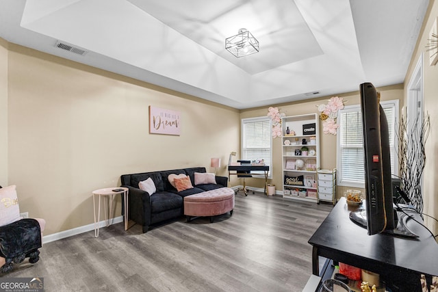 living room featuring hardwood / wood-style flooring and a tray ceiling