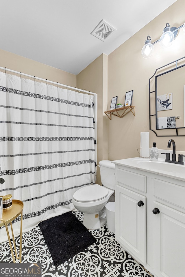 bathroom with toilet, vanity, and tile patterned flooring