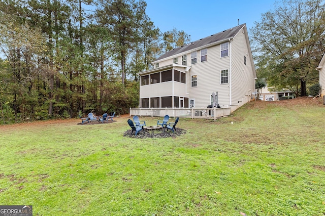 back of house featuring a fire pit, a sunroom, and a yard