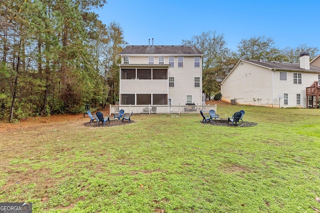 rear view of property with an outdoor fire pit, a lawn, and a sunroom