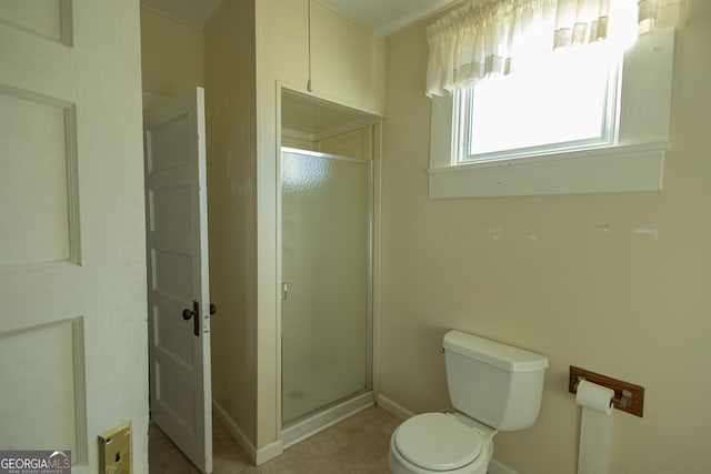 bathroom featuring a shower with shower door and toilet