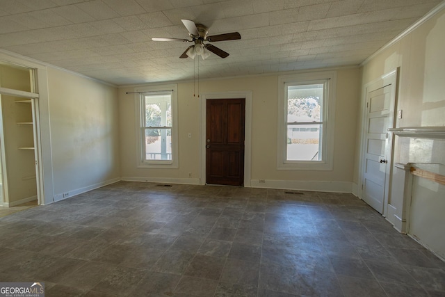 empty room featuring ceiling fan, a wealth of natural light, and ornamental molding