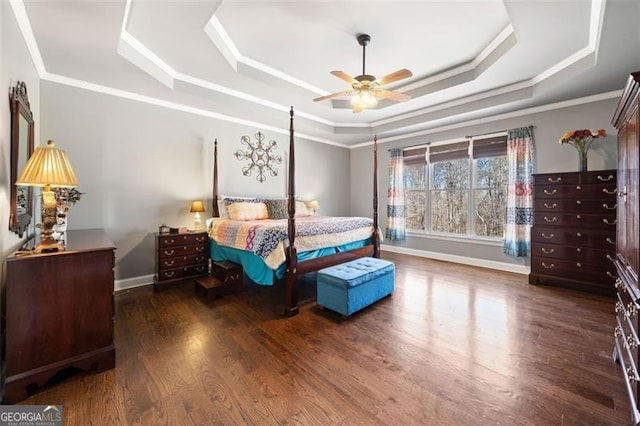 bedroom with ceiling fan, dark hardwood / wood-style flooring, ornamental molding, and a tray ceiling