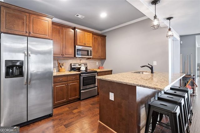 kitchen featuring decorative light fixtures, stainless steel appliances, an island with sink, ornamental molding, and sink