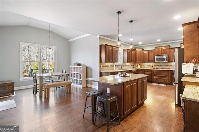 kitchen with stainless steel appliances, decorative light fixtures, a center island, and lofted ceiling