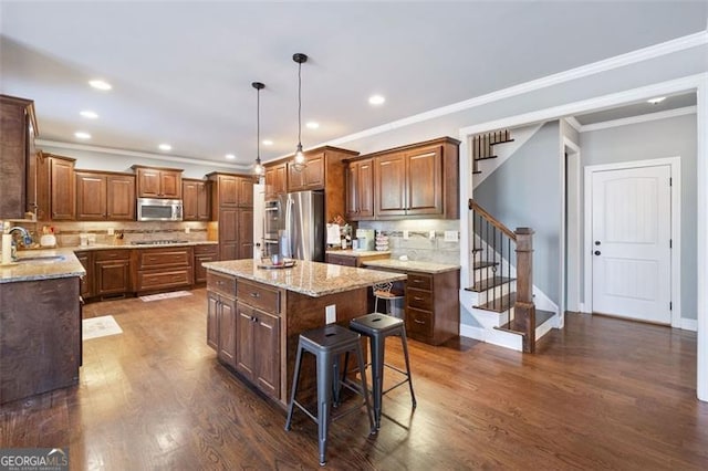 kitchen with a kitchen island, appliances with stainless steel finishes, backsplash, and hanging light fixtures