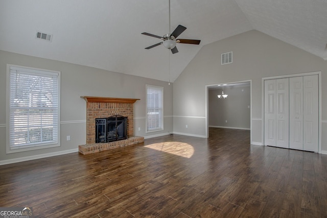 unfurnished living room featuring ceiling fan with notable chandelier, a brick fireplace, vaulted ceiling, and dark hardwood / wood-style floors