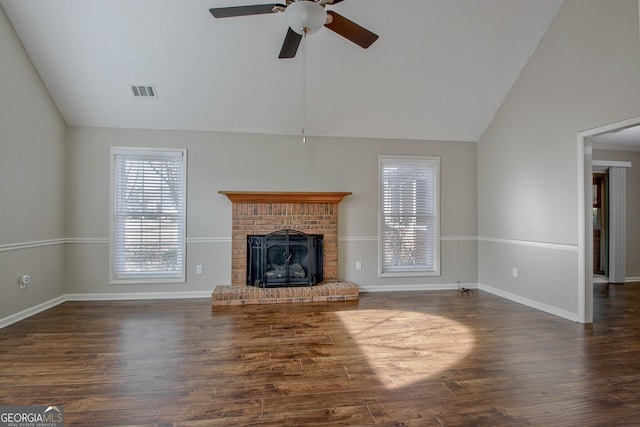 unfurnished living room featuring lofted ceiling, dark hardwood / wood-style flooring, a brick fireplace, and ceiling fan