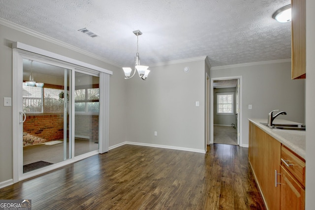 unfurnished dining area with sink, dark wood-type flooring, a notable chandelier, and a textured ceiling