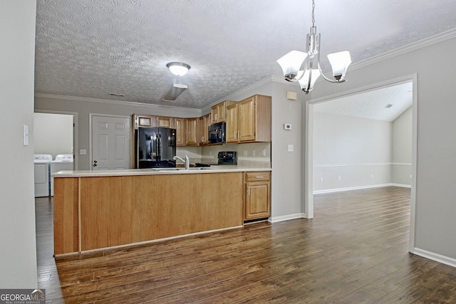 kitchen featuring black appliances, hanging light fixtures, washing machine and dryer, crown molding, and an inviting chandelier