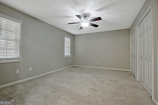 unfurnished bedroom featuring light colored carpet, ceiling fan, and a textured ceiling