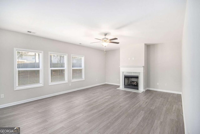 unfurnished living room with ceiling fan, light hardwood / wood-style flooring, and a fireplace