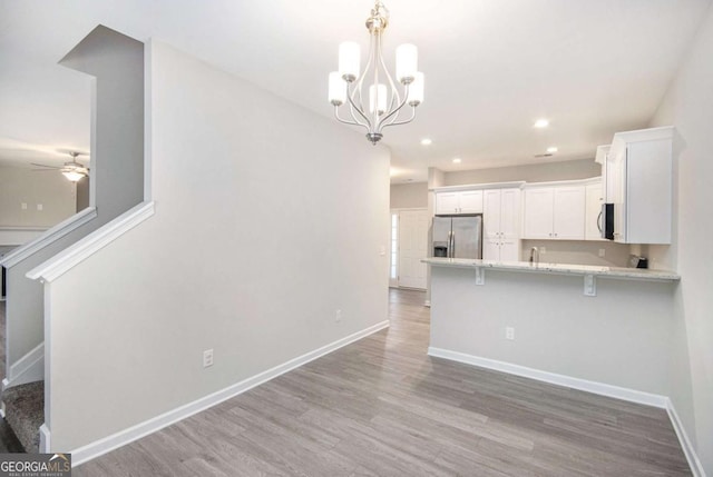 kitchen featuring kitchen peninsula, light hardwood / wood-style floors, a breakfast bar area, white cabinets, and appliances with stainless steel finishes