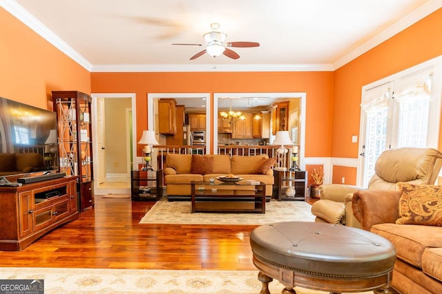 living room with ceiling fan with notable chandelier, hardwood / wood-style flooring, and ornamental molding