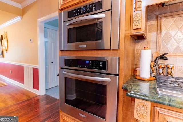 kitchen with ornamental molding, dark hardwood / wood-style flooring, stainless steel oven, and tasteful backsplash