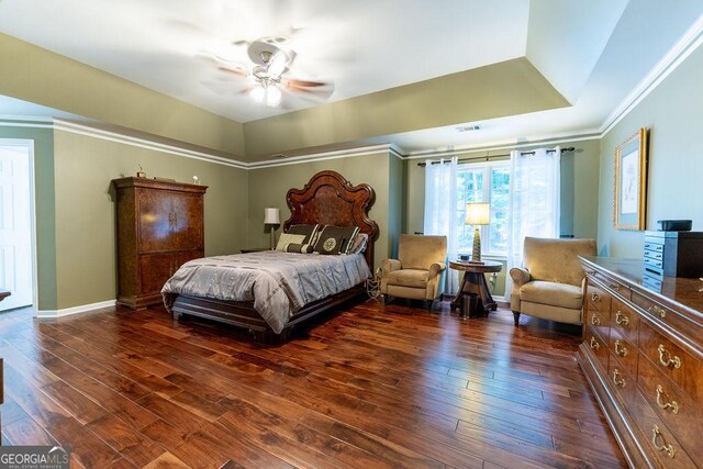 bedroom featuring ceiling fan, dark hardwood / wood-style flooring, a raised ceiling, and crown molding