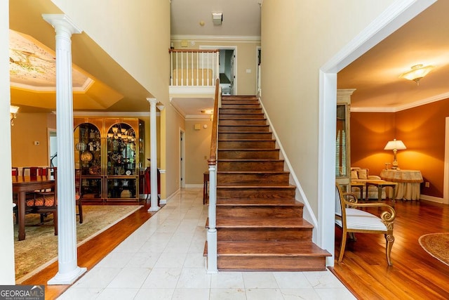 staircase featuring ornate columns, wood-type flooring, and crown molding