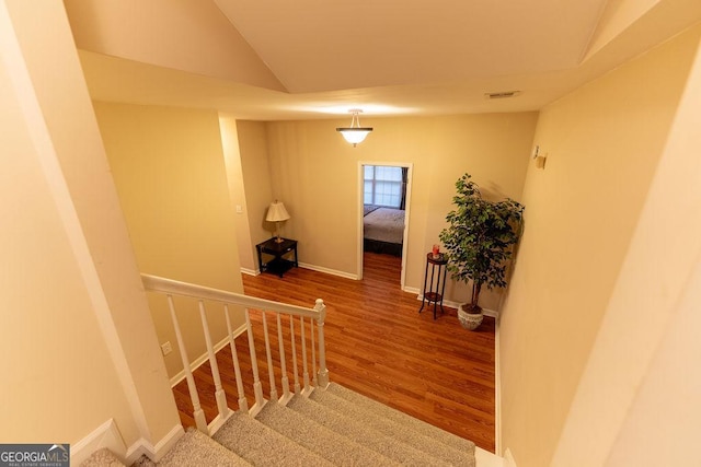 stairs with hardwood / wood-style flooring and vaulted ceiling